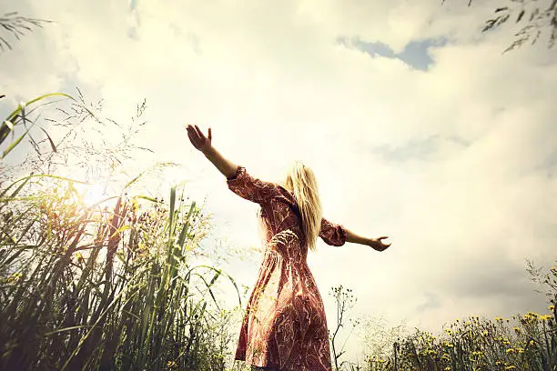 Photo of young woman enjoying nature in the middle of a meadow