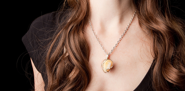 An orange calcite semi-precious stone in a handcrafted necklace charm.