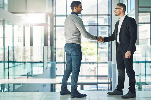 Shot of two businessmen shaking hands together in an office
