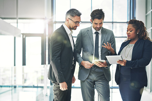 Shot of a group of coworkers talking together over a digital tablet in an office