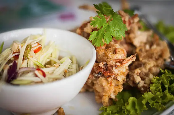 Soft shell crab fried crispy  The salad with a mixture of mango . Photo by Focus Near distance of acceptable sharpness in cup Soft shell crab salad and fried crispy in parts .