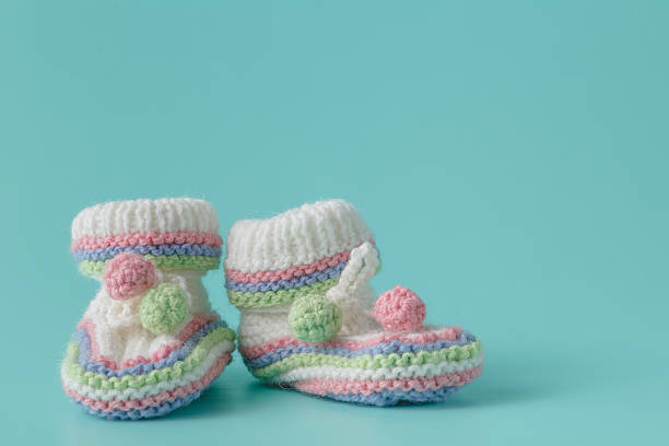istock Newborn announcement. knitted baby booties on plain aquamarine b 524379890