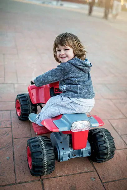 Photo of Smiling little kid having fun on an ATV.