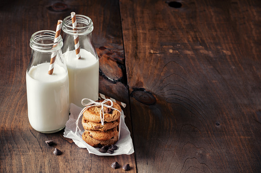 Milk bottles and chocolate chips cookies. Toned image. Selective focus on cookies.