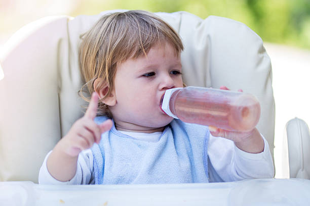 istock Baby boy relaxing in high chair while drinking from bottle. 524391474