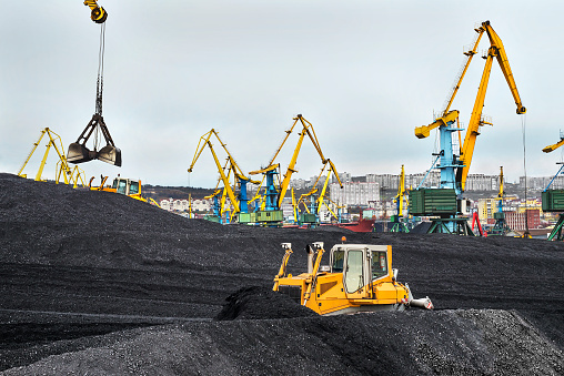 Coal Mountain, bulldozer, cargo cranes in the territory of the commercial seaport of Murmansk (Russia)