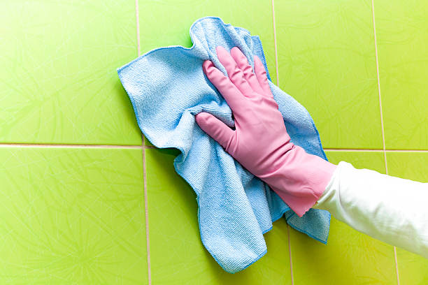istock Protective glove cleaning tiles with blue rag. Maid cleans house. 524395064