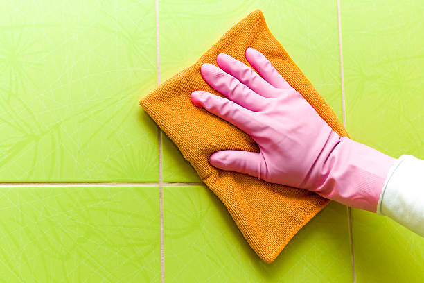 istock Protective glove cleaning tiles with orange rag. Maid cleans house. 524395594