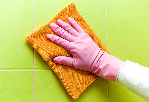 istock Protective glove cleaning tiles with orange rag. Early spring cleaning. 524395626