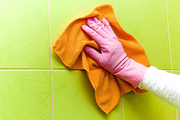 istock Protective glove cleaning tiles with orange rag. Early spring cleaning. 524395668