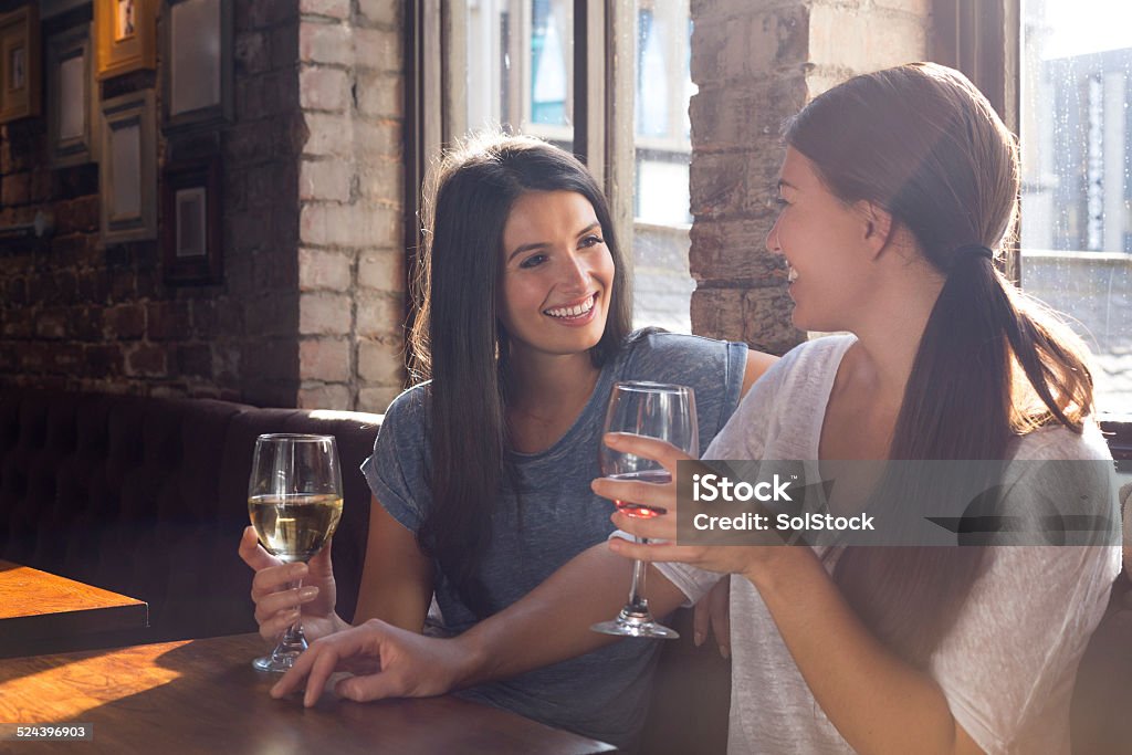 Two Women Enjoying a Drink Together Two women enjoying a drink together in a bar. Wine Stock Photo