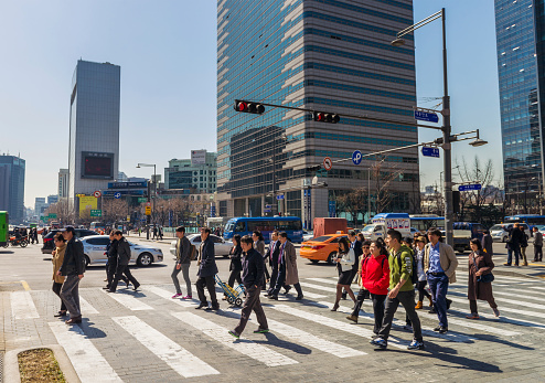 People crossing the street at a road intersection in the Jongno District, in Seoul's city centre.