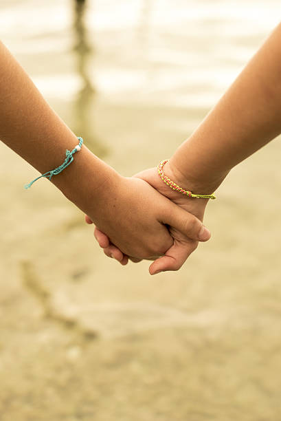istock Close up of kids holding hands on beach concept 524397340