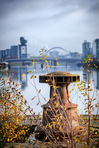 Derelict Graving Docks at Govan, Glasgow A rusting only iron capstan amongst the overgrowth at the derelict Victorian graving docks - a type of dry dock - in Govan, Glasgow, on the River Clyde. In the background is the modern Glasgow skyline. govan stock pictures, royalty-free photos & images