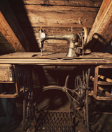 An antique sewing machine sits in the attic of an abandoned home.