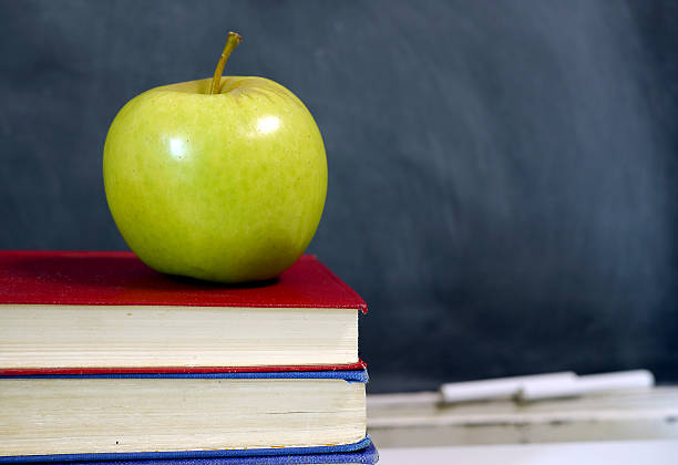 istock green apple in pile of books in classroom 524397783