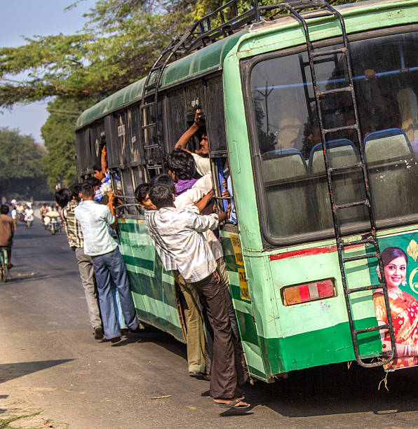 Tiruvannamalai, India - February 5, 2014: Crowded bus with people hanging outside is a common sight in India. The bus runs around the sacred mountain of Arunachala, and on every full moon, large crowds of people will gather and walk the 12 km circular road on foot.