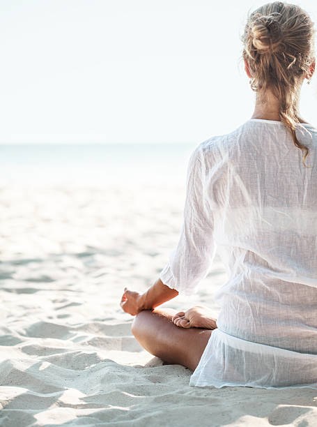 istock Young woman sitting on the  beach and meditating 524398414