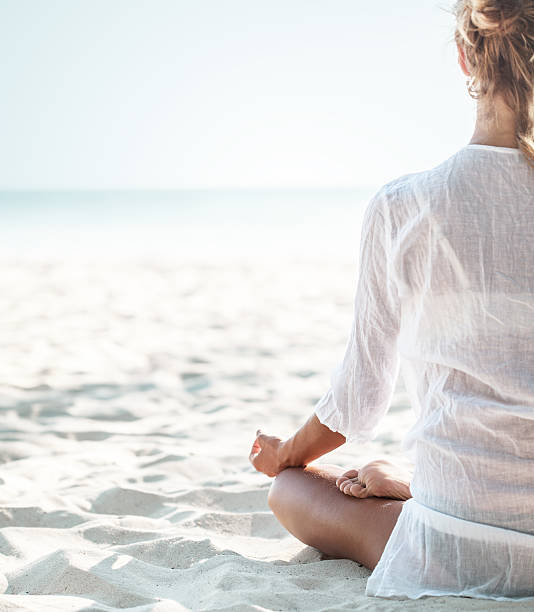 istock Young woman sitting on the  beach and meditating 524398456