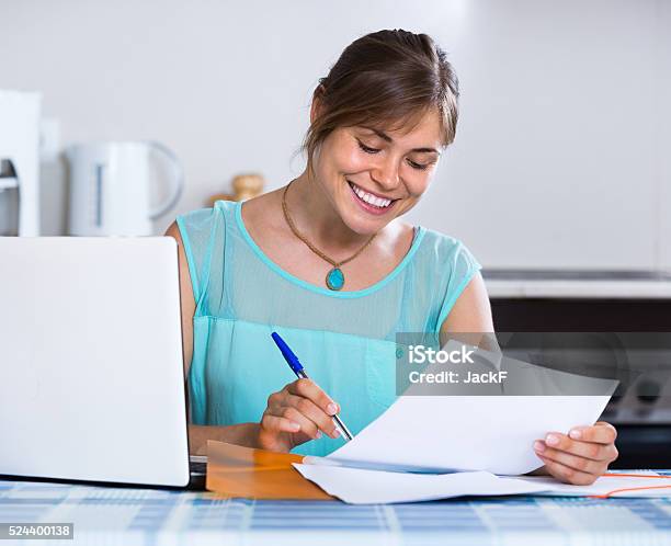 Smiling Woman With Documents At Kitchen Stock Photo - Download Image Now - 25-29 Years, Adult, Adults Only