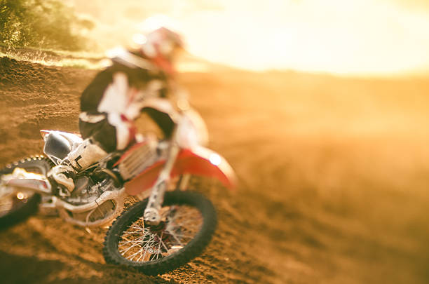 Motocross racer making a turn in dirt track with selective focus on his bike
