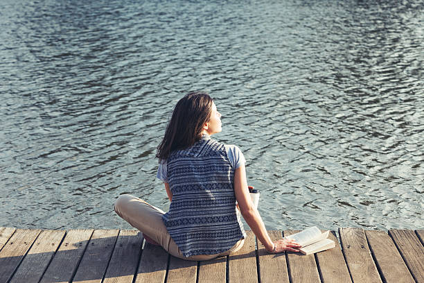 istock handsome girl with reading a book on a pier 524403099