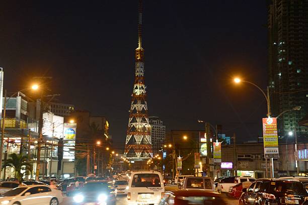 Quezon City, Philippines - January 24, 2014: Night heavy traffic speed motion in Cubao, a busy nightlife and shopping area in Quezon City, Metro-Manila. In the background is the 219,5 m high Millennium Transmitter, also called ABS-CBN Tower, a tall communications tower who dominates on the Cubao area.