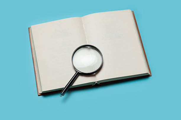 istock Opened book and loupe on color background. 524449495