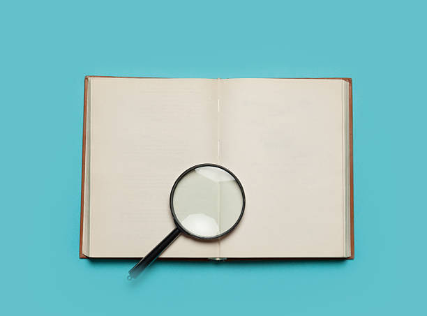 istock Opened book and loupe on color background. 524449497