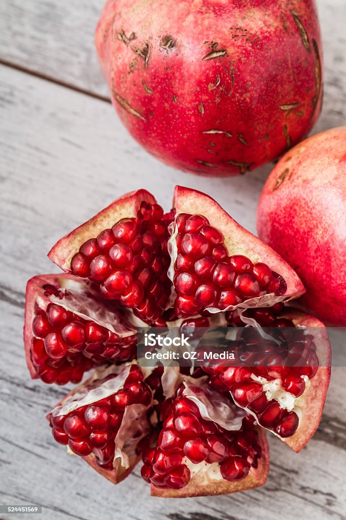 Juicy Pomegranates Half pomegranate and raw pomegranates on a white wooden background Agriculture Stock Photo