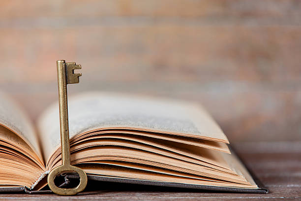 istock Retro key and opened book on wooden table. 524451603