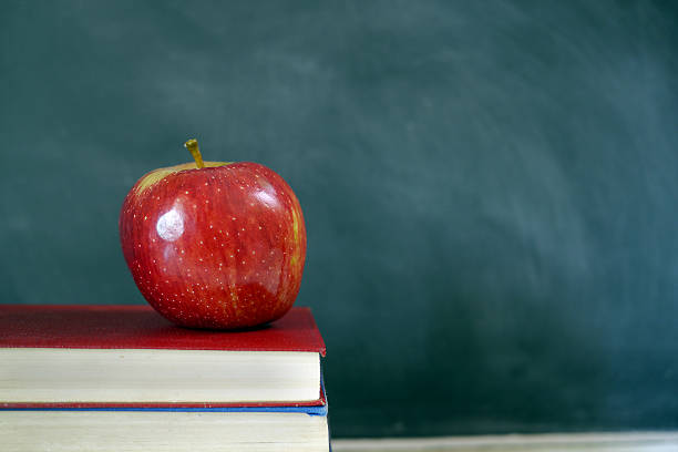istock red apple and books in front of chalkboard 524451817