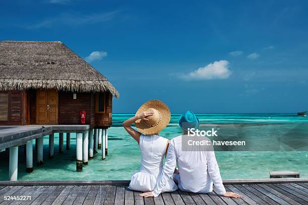 Couple On A Beach Jetty At Maldives Stock Photo - Download Image Now - Maldives, Couple - Relationship, Vacation Rental