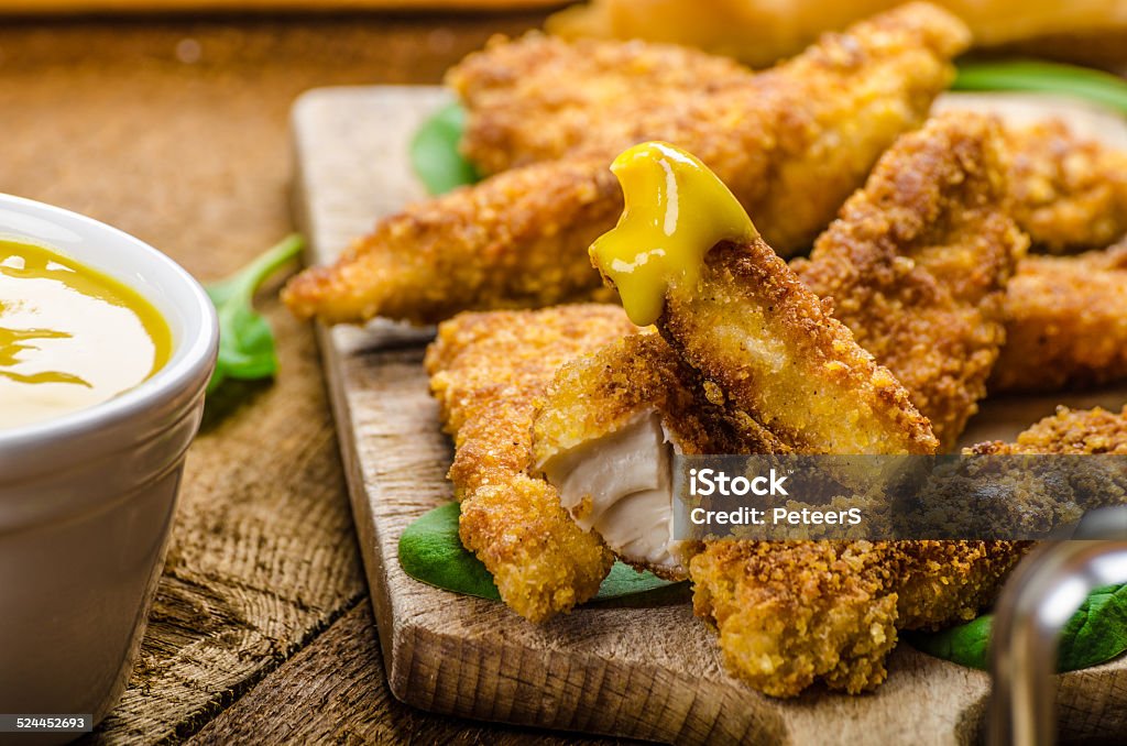 Corn crusted Chicken Tenders Corn crusted Chicken Tenders with spinach and toast, honey-dijon mustard dip, homemade bread baguette Honey Stock Photo