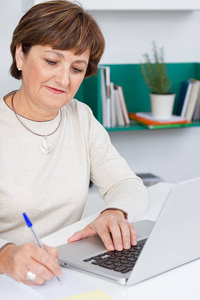 istock Senior woman taking notes with laptop 524455299