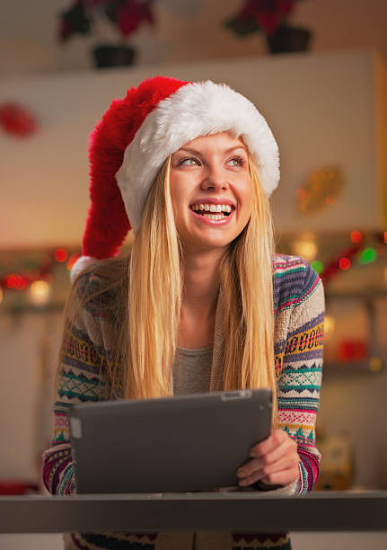 istock happy teenage girl in santa hat using tablet pc 524479671