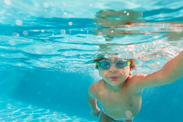 istock Small boy swimming wearing goggles under water 524508343