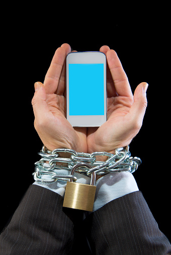 Hands of caucasian businessman addicted to mobile phone bond and locked with iron chain wrists in smartphone internet addiction and slave to online network addict concept