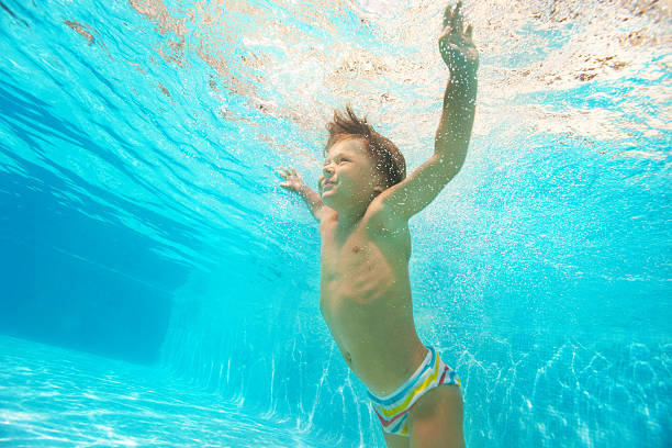 istock Boy swimming up with arms apart under water 524508691