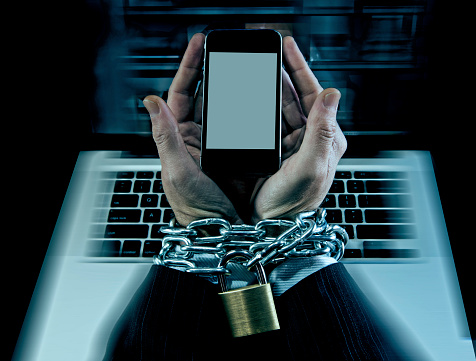 Hands of caucasian businessman addicted to mobile phone bond and locked with iron chain wrists in smartphone internet addiction and slave to online network addict concept