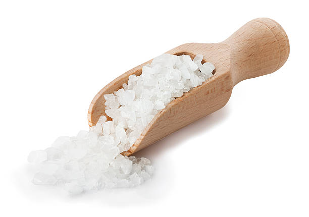 Sea salt poured from wooden scoop stock photo