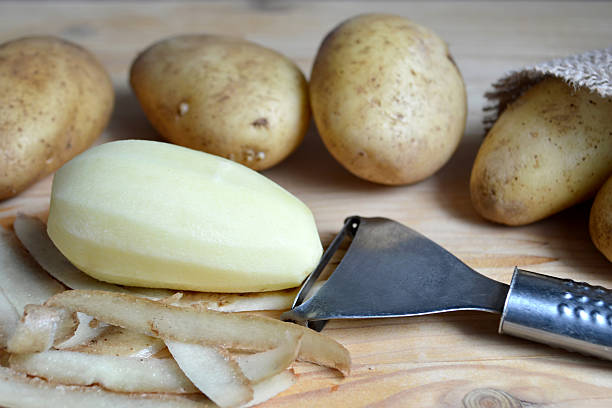 istock Peeled  potato and potato peeler 524530432