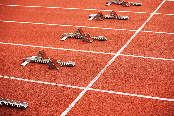 Some starting block on running track Five empty starting blocks on stadium. Diagonal composition. start block stock pictures, royalty-free photos & images