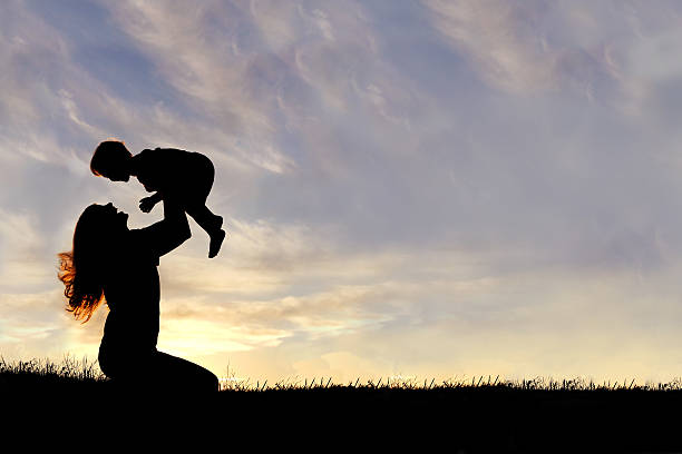 silhouette di felice madre con bambino che giocano all'aperto - christin foto e immagini stock