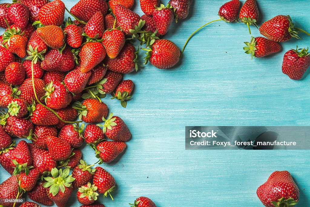 Strawberries over turquoise blue painted wooden background Summer fruit food frame. Strawberries over turquoise blue painted wooden background. Top view, copy space Strawberry Stock Photo