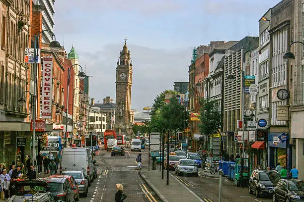 Downtown Belfast indicating shoppers, stores, traffic, cars, and the leaning clock tower.