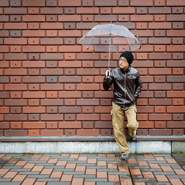 istock Asian Man in a Brown Jacket With a Clear Umbrella 524537940