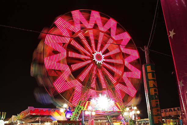 istock amusement park: bright trails of ferris wheel in motion 524540727