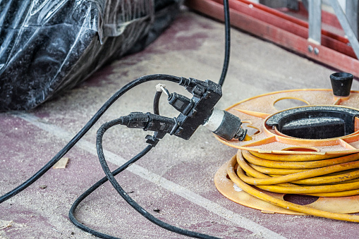 Several electric power tool cords are connected to a single - almost certainly overloaded - 