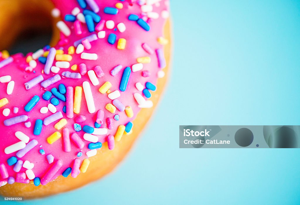 Donut with pink icing and sprinkles on blue background Doughnut Stock Photo